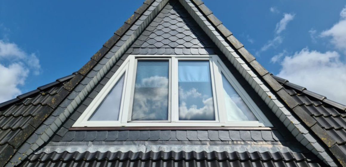 Open roof window in velux style with black roof tiles