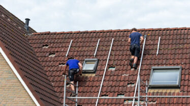 Two man on a tiled roof preparing the installation of solar panels
