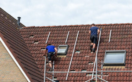 Two man on a tiled roof preparing the installation of solar panels